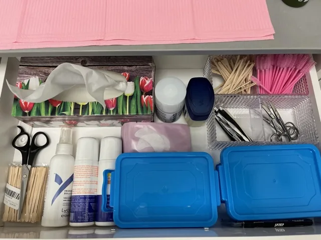 Organized studio drawer with waxing spatulas, gloves, cotton pads, and treatment supplies